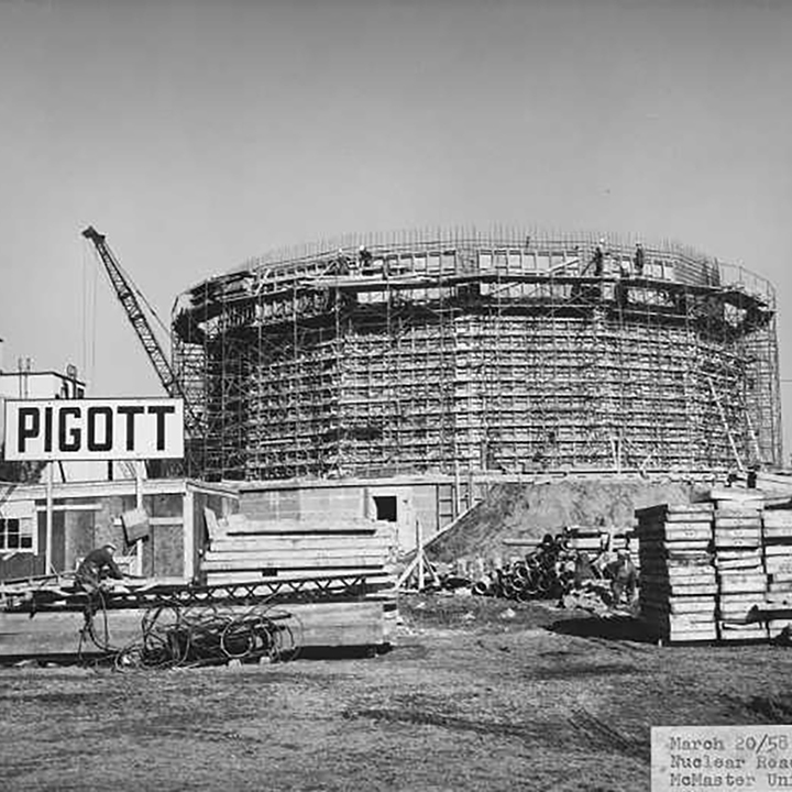 A round building has
scaffolding surrounding it and piles of construction supplies rest in
front. To the left of the building, there is a construction trailer with a
construction company sign that reads “PIGOTT.”
