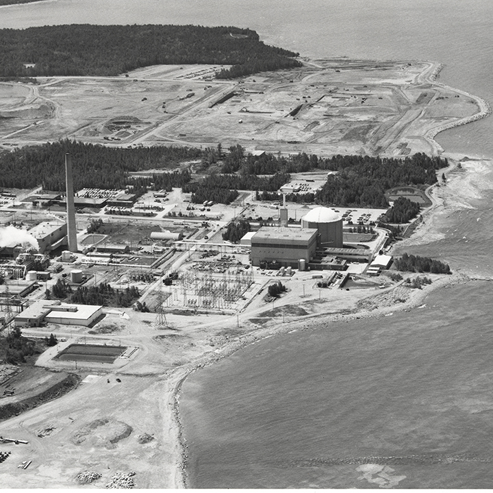 Aerial view of Douglas
Point Nuclear Generating Station, including a long shoreline, several
buildings and a smokestack. 