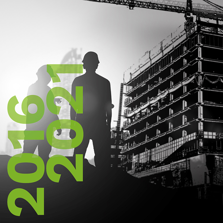Rétrospective de 2016 à 2021. La silhouette de deux hommes en
casques de sécurité apparaît devant un chantier de construction.