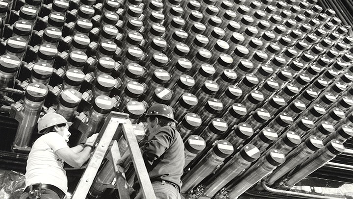 Deux travailleurs se tiennent devant la face du réacteur de Bruce Power pendant sa phase d’exploitation, vers les années 1990.]