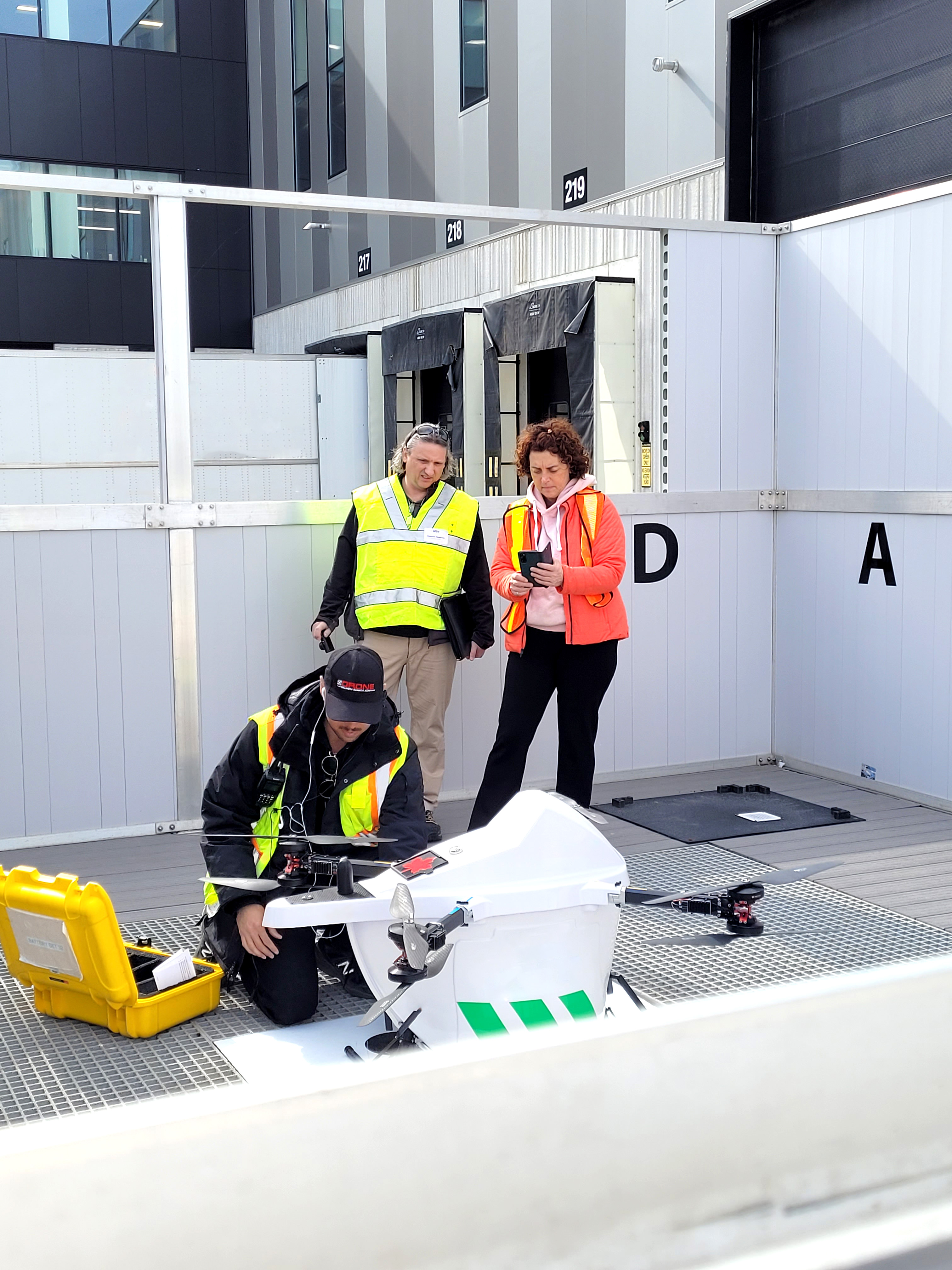 CNSC inspectors overseeing a technician preparing a drone for the transport of medical isotopes.