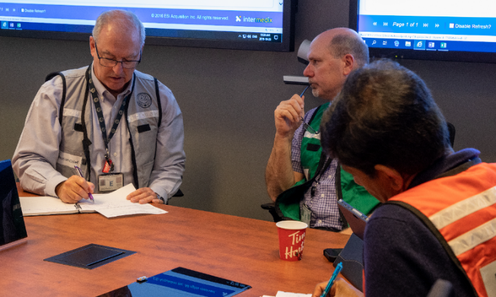 CNSC staff in the Emergency Operations Centre work through the status of the exercise event.