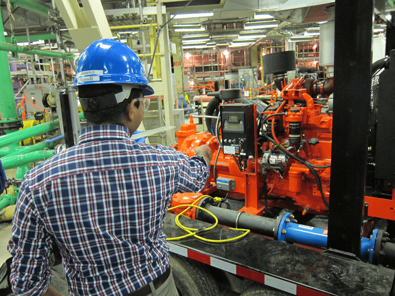 Photo of a CNSC staff member inspecting portable diesel emergency water pumps. These can be used in emergency situations to keep water circulating in the reactor.
