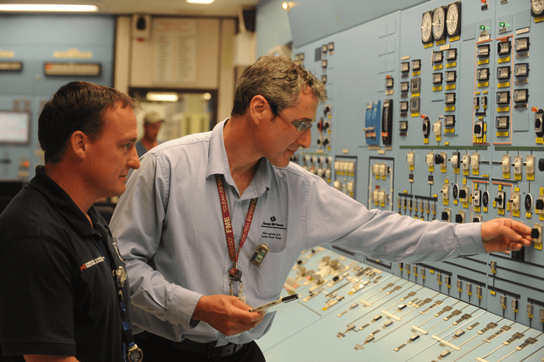 Text Box: Un opérateur de salle de commande et un inspecteur de la CCSN à Point Lepreau. Les principaux postes liés à la sureté des centrales nucléaires, comme celui d’opérateur de réacteur, doivent être occupés par des personnes accréditées par la CCSN. L’accréditation délivrée par la CCSN signifie que ces personnes ont reçu la formation appropriée et possèdent les qualifications et la capacité pour exercer leurs fonctions.
