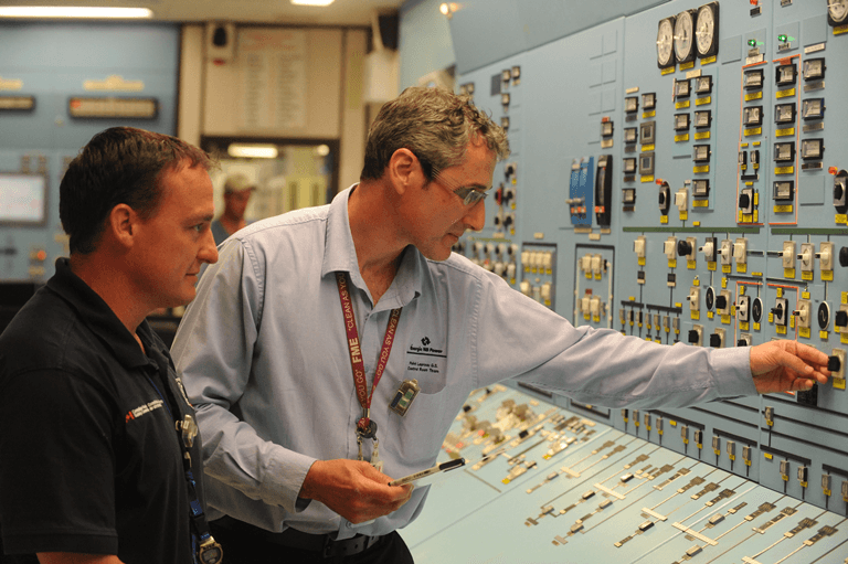 Photo of a control room operator and a CNSC inspector working in the Point Lepreau control room