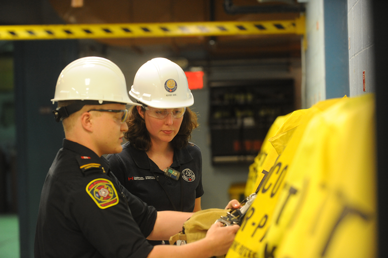 Photo of two workers inspecting emergency response equipment at Point Lepreau