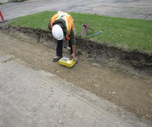 Worker operating a portable gauge to measure soil characteristics