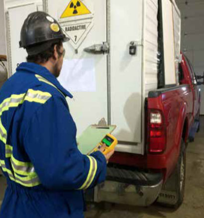 A Radiation Protection Officer inspecting the back of a pickup truck carrying a sealed source.