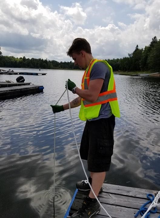 Un employé de la CCSN prélevant un échantillon de sédiment  à proximité des sites miniers de Bancroft en 2019.