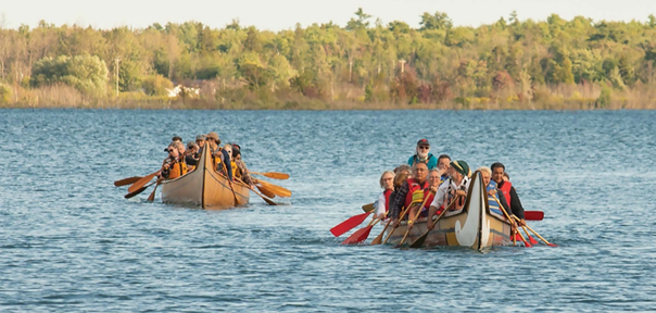 Image de canoës de voyageurs transportant des dirigeants, des dignitaires et le vice-président de la SGDN chargé de la sélection du site, marquant le début de l’Assemblée générale annuelle de la Nation métisse de l’Ontario