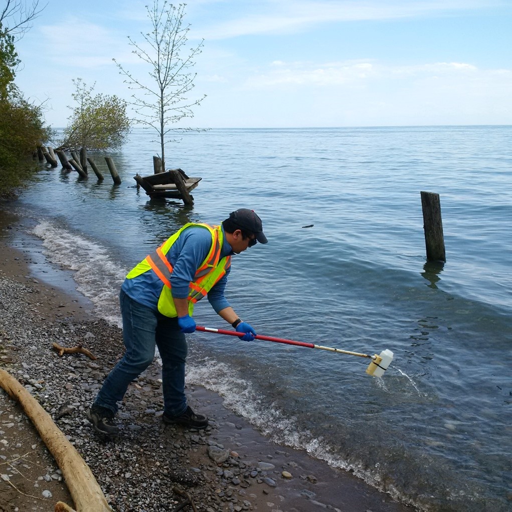 Un employé de la CCSN qui prélève des échantillons d’eau le long des berges du lac Ontario à Port Hope.