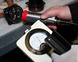 A radiation detection instrument is being used to identify an aircraft instrument that contains radium paint.
