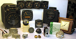 Pictured are a number of devices that contain radium luminous compounds. The devices include vintage military aircraft instruments, toggle switches, vintage consumer timepieces including a pocket watch and a travel alarm clock, instrument knobs, a circuit breaker, and drawer pulls.
